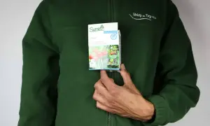 Osoba w zielonej bluzie trzyma opakowanie środka ochrony roślin Revus. Opakowanie zawiera informacje o zastosowaniu i zdjęciach pomidorów.